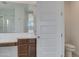 Bathroom with a white door, brown vanity, mirror, walk-in shower, and white toilet showcasing a modern design at 17033 W Royal Palm Rd, Waddell, AZ 85355