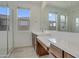 Bright bathroom featuring dual sinks with quartz countertops, large mirror, and glass enclosed shower at 17033 W Royal Palm Rd, Waddell, AZ 85355