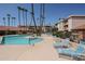 Community pool with lounge chairs and palm trees on a bright sunny day at 17404 N 99Th Ave # 214, Sun City, AZ 85373