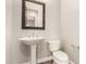 Powder bathroom featuring white pedestal sink, toilet, decorative mirror, and neutral wall color at 17953 W Willow Dr, Goodyear, AZ 85338