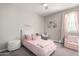 Charming bedroom features soft pink decor, a cozy bed, and a window bringing natural light for a serene and comfortable space at 18735 W San Juan Ave, Litchfield Park, AZ 85340