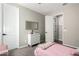 A bedroom with light-colored walls, a white dresser, a doorway, and a bed with pink bedding and decor at 18735 W San Juan Ave, Litchfield Park, AZ 85340