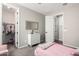 A bedroom with light-colored walls, a white dresser, a view into the closet, and a bed with pink bedding and decor at 18735 W San Juan Ave, Litchfield Park, AZ 85340