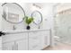 Bright bathroom with double vanity, round mirrors, and glass door shower at 20453 N 95Th Pl, Scottsdale, AZ 85255