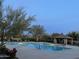 Community pool with lounge chairs and covered patio, illuminated by outdoor lighting at 29031 N 125Th Ln, Peoria, AZ 85383
