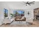 Spacious living room with a stone fireplace, modern furniture, and bright natural light from large windows at 3517 E Hartford Ave, Phoenix, AZ 85032
