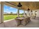 Beautifully covered patio with an outdoor dining area and manicured backyard with mature trees at 4037 E Minton Cir, Mesa, AZ 85215