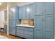 A luxurious laundry room featuring blue cabinets, quartz countertops, and sleek golden hardware accents at 4037 E Minton Cir, Mesa, AZ 85215