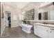 Elegant bathroom features a soaking tub, dual sinks, and a stylish grid mirror at 6328 W Fetlock Trl, Phoenix, AZ 85083