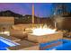 Inviting poolside fire pit area with comfortable seating and ambient lighting at 6328 W Fetlock Trl, Phoenix, AZ 85083