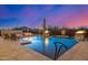 Stunning pool area with outdoor seating and rock waterfall with a picturesque sunset at 6328 W Fetlock Trl, Phoenix, AZ 85083