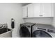 Modern laundry room with white cabinets, stainless steel washer and dryer, and a utility sink at 8618 E Via De Encanto --, Scottsdale, AZ 85258