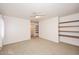 Bedroom with tan carpet, ceiling fan, built-in shelving and a view of the hallway at 9512 E Kilarea Ave, Mesa, AZ 85209