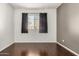 This bedroom offers natural light from the window and has dark curtains and hardwood flooring at 955 E Knox Rd # 224, Chandler, AZ 85225