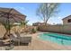 Relaxing backyard with lounge chairs next to a refreshing pool, shaded by a large patio umbrella at 1061 E Poncho Ln, San Tan Valley, AZ 85143