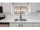 Bright kitchen features stainless steel sink with a black faucet and marble countertops and white cabinetry at 1061 S Palo Verde St, Mesa, AZ 85208