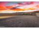 Spacious desert landscape backyard, featuring a tall brick wall and vibrant sunset backdrop at 11366 W Ashby Dr, Peoria, AZ 85383