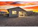 Desert landscape backyard featuring a covered patio with dining and seating areas, highlighted by a dramatic sunset at 11366 W Ashby Dr, Peoria, AZ 85383