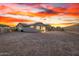 Expansive desert landscaped backyard showcasing a covered patio with stylish seating, illuminated by a colorful sunset at 11366 W Ashby Dr, Peoria, AZ 85383