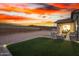 Large backyard featuring desert landscaping, a covered patio with outdoor seating, and a striking sunset backdrop at 11366 W Ashby Dr, Peoria, AZ 85383