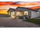 Backyard showcasing a covered patio with dining and seating areas, complemented by desert landscaping and a vibrant sunset at 11366 W Ashby Dr, Peoria, AZ 85383