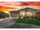 Charming single-story home with a well-manicured lawn and inviting front porch, illuminated by a colorful sunset at 11366 W Ashby Dr, Peoria, AZ 85383