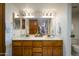 Bathroom with a double sink vanity, wood cabinets, and a large mirror reflecting the bedroom at 12212 N Paradise Village S Pkwy # 136, Phoenix, AZ 85032