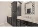 Bathroom with black cabinetry, dual sinks, a framed mirror, and white countertops at 15480 W Corrine Dr, Surprise, AZ 85379