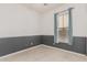 Bedroom showcasing light tile floors, gray wainscoting, white walls, and a window with light blue curtains at 15480 W Corrine Dr, Surprise, AZ 85379