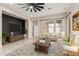 Bright living room featuring a modern ceiling fan, stylish furniture, a rustic accent wall, and lots of natural light at 15480 W Corrine Dr, Surprise, AZ 85379