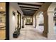 Covered walkway showing travertine floors, arched columns, wood beams, and black trimmed doors and windows at 19978 N 101St Pl, Scottsdale, AZ 85255