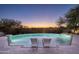 Backyard pool view with lit lounge chairs and sunset sky at dusk with mountain view in the distance at 19978 N 101St Pl, Scottsdale, AZ 85255