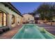 Backyard view featuring pool, outdoor kitchen and covered walkway against an exterior elevation at dusk at 19978 N 101St Pl, Scottsdale, AZ 85255