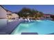 Backyard pool view showing in-pool loungers, outdoor kitchen, and view of other houses at twilight at 19978 N 101St Pl, Scottsdale, AZ 85255