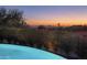 Backyard pool and hillside view featuring desert foliage, mountain views, and sunset sky at dusk at 19978 N 101St Pl, Scottsdale, AZ 85255