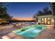 Backyard pool view showing a lit waterfall feature, travertine tile, and a peek of the sunset sky at 19978 N 101St Pl, Scottsdale, AZ 85255