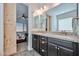 Bathroom featuring double sinks with granite counters, framed glass shower, and adjacent bedroom access at 20231 W Grant St, Buckeye, AZ 85326