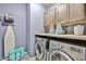 Laundry room with front loading machines, wooden cabinets, and countertop space for folding and organizing laundry at 20231 W Grant St, Buckeye, AZ 85326