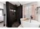 Bathroom view featuring modern tub with black fixtures and tiled shower, complemented by natural light and shuttered window at 2435 W Via Dona Rd, Phoenix, AZ 85085