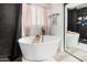 Bright bathroom features a modern freestanding tub with black fixtures, a dark tiled shower, and shuttered windows at 2435 W Via Dona Rd, Phoenix, AZ 85085