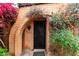 The property's entrance with an arched brick doorway and wrought iron security gate, framed by climbing vines and foliage at 3046 N 32Nd St # 328, Phoenix, AZ 85018