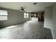 Open-concept living room with tile flooring, large windows, ceiling fan, and seamless flow to the kitchen at 34997 N Sacramento Wash Rd, San Tan Valley, AZ 85144