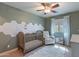 A cozy Bedroom with gold star wallpaper, crib, white rocker, white shelves, and plush rug at 3507 E Jasper Dr, Gilbert, AZ 85296