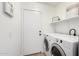 Well-lit laundry area with a washer and dryer next to the entry door at 43795 W Sagebrush Trl, Maricopa, AZ 85138