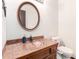 Bathroom featuring sink with tile countertop, round mirror, and toilet at 4721 W Eva St, Glendale, AZ 85302