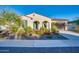 Single-story home featuring desert landscaping with colorful flowering bushes, stucco exterior, and arched entryway at 5245 N 205Th Ln, Buckeye, AZ 85396