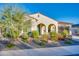 Charming single-story home featuring a desert landscape with colorful flowering bushes and a stucco exterior, with arched entryway at 5245 N 205Th Ln, Buckeye, AZ 85396