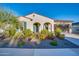 Single-story home with arched entryway, desert landscaping and flowering bushes with a stucco exterior and attached garage at 5245 N 205Th Ln, Buckeye, AZ 85396