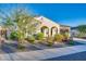 Charming single-story home featuring a desert landscape with colorful flowering bushes and a stucco exterior, with arched entryway at 5245 N 205Th Ln, Buckeye, AZ 85396