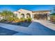 Single-story home with arched entryway, desert landscaping and flowering bushes, a stucco exterior and attached garage at 5245 N 205Th Ln, Buckeye, AZ 85396